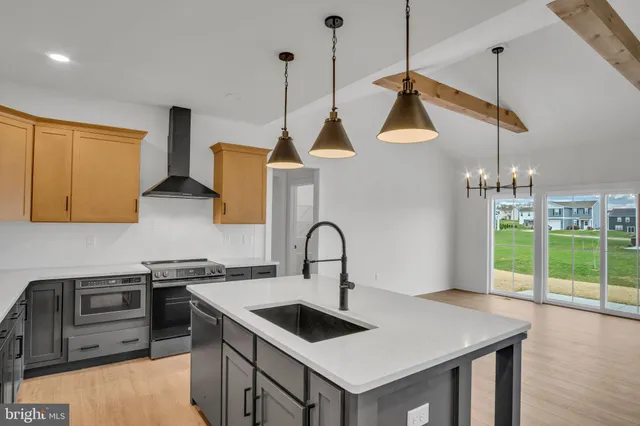 a kitchen with a stove a sink a kitchen island with wooden cabinets and floor