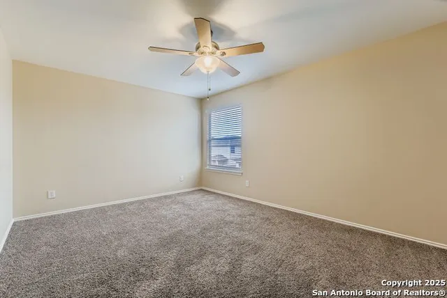 an empty room with a ceiling fan and wooden floor