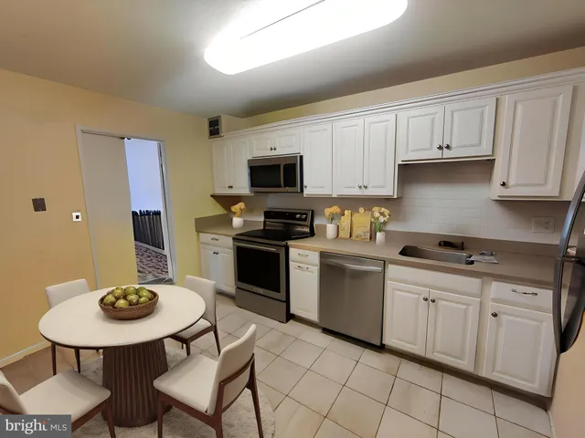 a kitchen with a sink white cabinets and stainless steel appliances