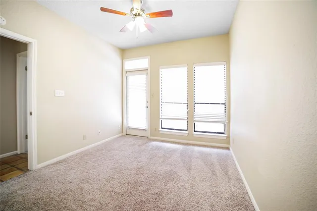 an empty room with windows and ceiling fan
