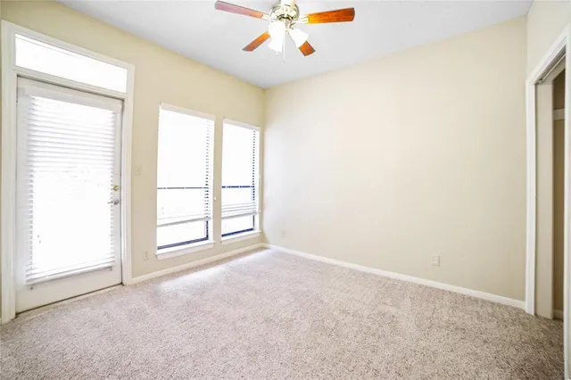 an empty room with windows and ceiling fan