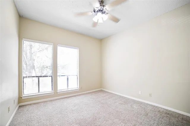 an empty room with windows and chandelier fan
