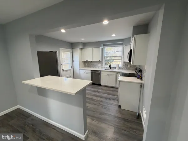 a kitchen with a refrigerator a sink dishwasher with a dining table and chairs