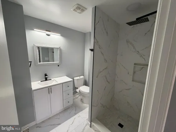 a bathroom with a shower sink mirror and toilet