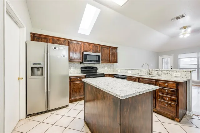 a kitchen with stainless steel appliances granite countertop a stove refrigerator sink and microwave