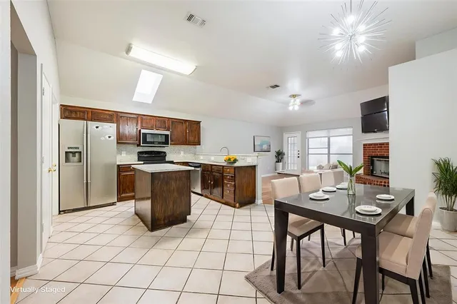 a kitchen with stainless steel appliances kitchen island granite countertop a refrigerator a stove a sink dishwasher and a dining table with wooden floor