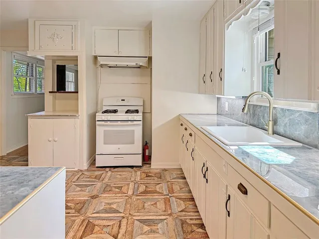 a kitchen with granite countertop a sink stove and cabinets