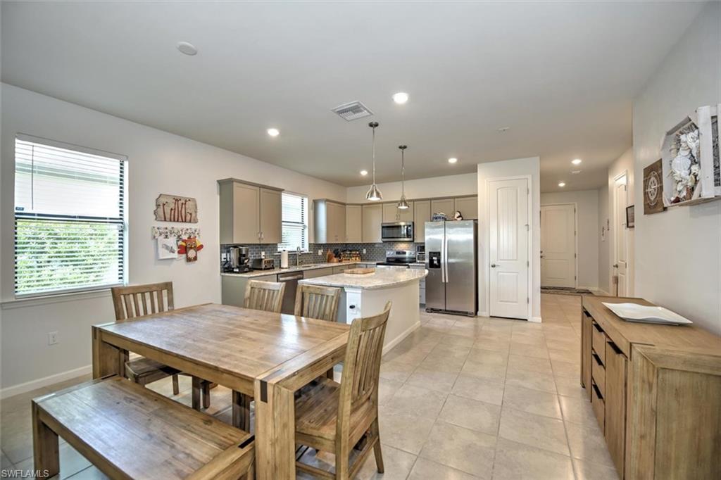 2106 Clementine Street Naples, FL 34120 - Photo 11 of 34 a kitchen with a table chairs refrigerator and microwave