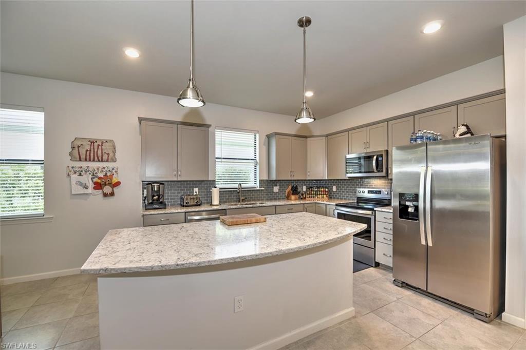 2106 Clementine Street Naples, FL 34120 - Photo 13 of 34 a kitchen with stainless steel appliances granite countertop a sink a stove a refrigerator cabinets and chairs