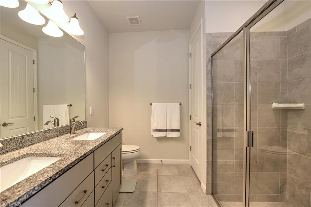 2106 Clementine Street Naples, FL 34120 - Photo 16 of 34 a bathroom with a granite countertop sink a mirror and a shower