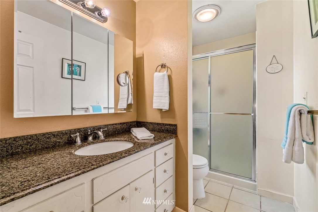 11812 Northeast 157th Street Bothell, WA 98011 - Photo 16 of 25 a bathroom with a granite countertop sink a mirror a vanity and a shower