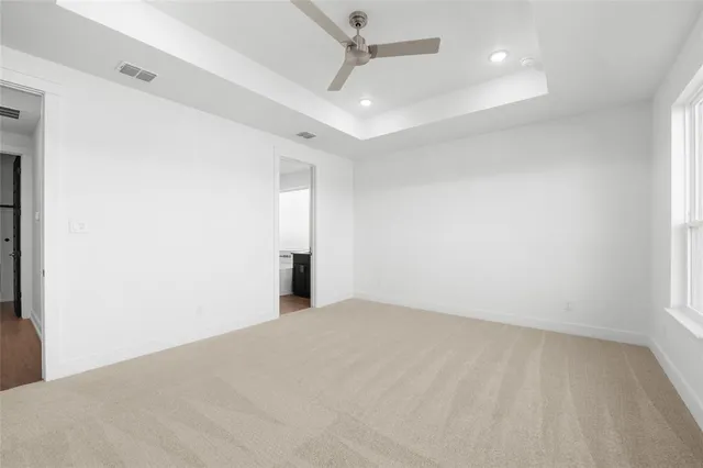 an empty room with chandelier fan and windows