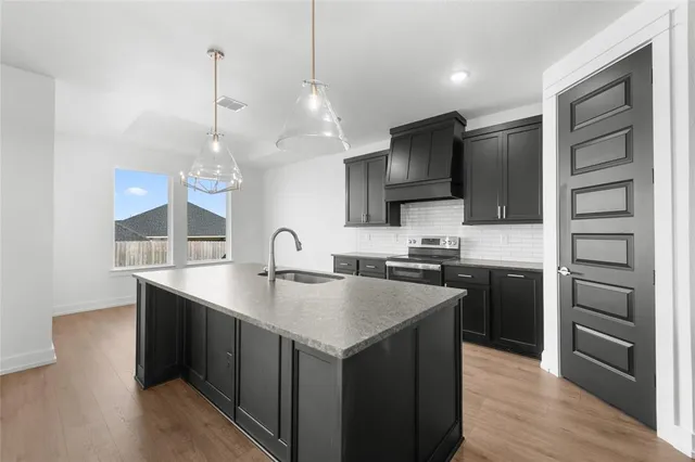 a kitchen with stainless steel appliances granite countertop a sink a stove and a wooden floors