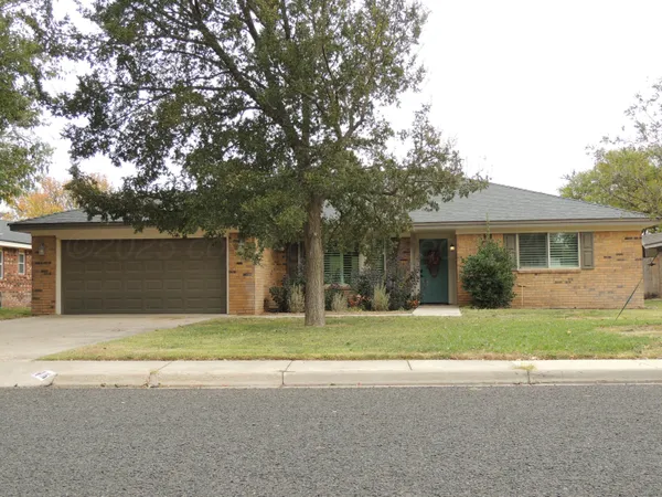 a view of a house with a yard and large tree