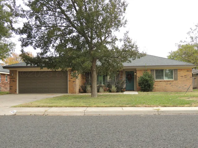 a view of a house with a yard and large tree