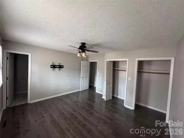 an empty room with wooden floor closet and windows