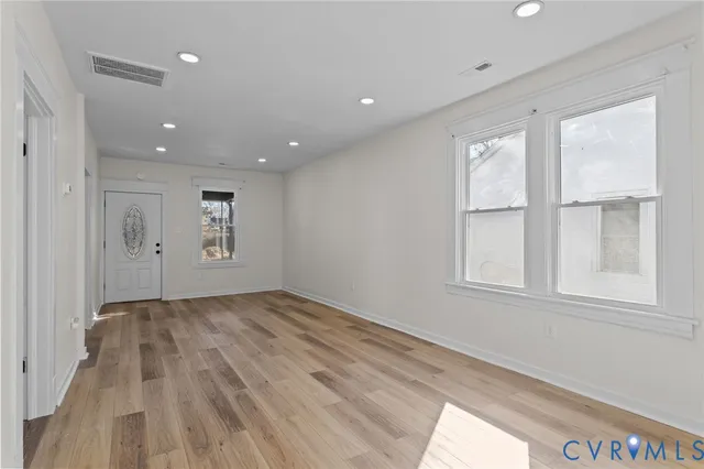 a view of empty room with wooden floor and fan