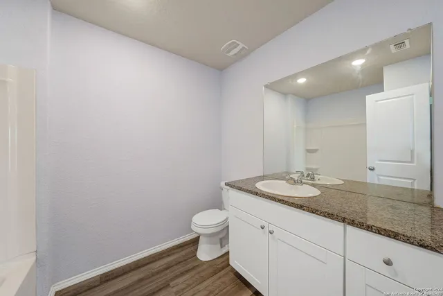 a bathroom with a granite countertop toilet a sink and a mirror