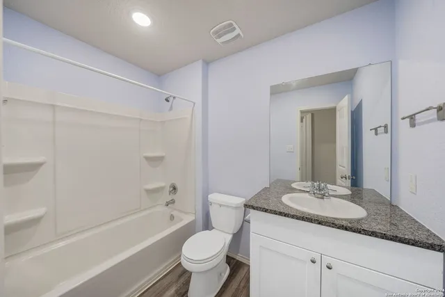 a bathroom with a granite countertop sink toilet mirror and bathtub