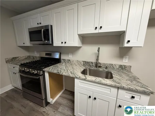 a kitchen with granite countertop white cabinets and stainless steel appliances
