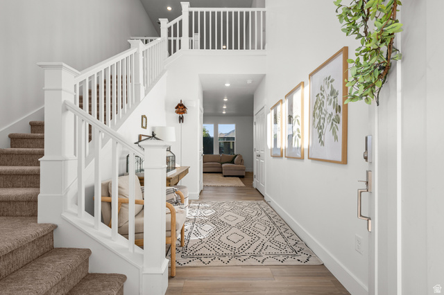 2706 West Maple Street, Unit 285 Mapleton, UT 84664 - Photo 5 of 36 Light-filled entryway featuring a two-story foyer, a grand staircase with white balusters, wood-finish flooring, recessed lighting, and a modern front door with brushed nickel hardware
