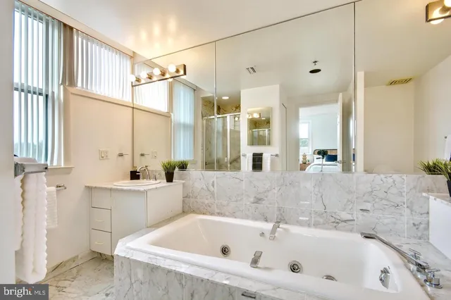a bathroom with a tub a sink and a large mirror
