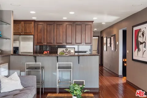 a living room with stainless steel appliances granite countertop furniture wooden floor and a large window