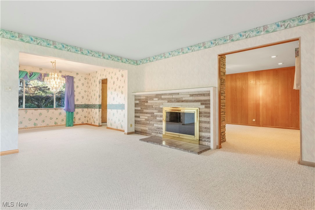 2490 Brice Road Akron, OH 44313 - Photo 7 of 42 Unfurnished living room featuring carpet floors, wooden walls, and a chandelier