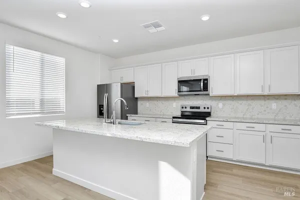 a kitchen with stainless steel appliances granite countertop a stove a sink a refrigerator a microwave and cabinets