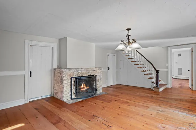 a view of an empty room with wooden floor fireplace and a window