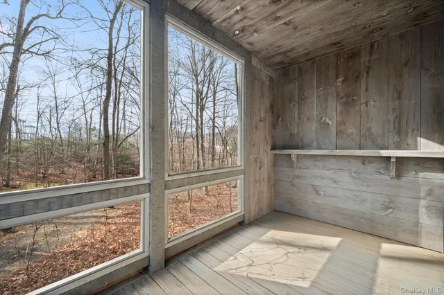 a view of an empty room with wooden floor fireplace and a window