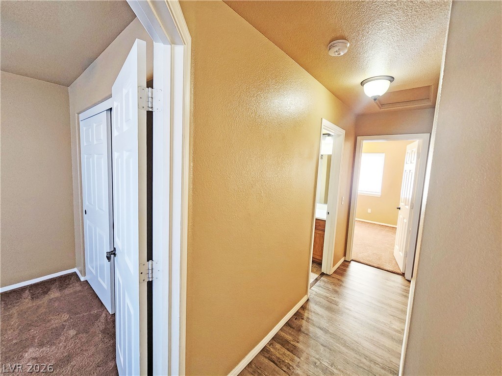 3680 Ravine Avenue Pahrump, NV 89048 - Photo 18 of 28 Corridor with attic access, a textured wall, a textured ceiling, and baseboards