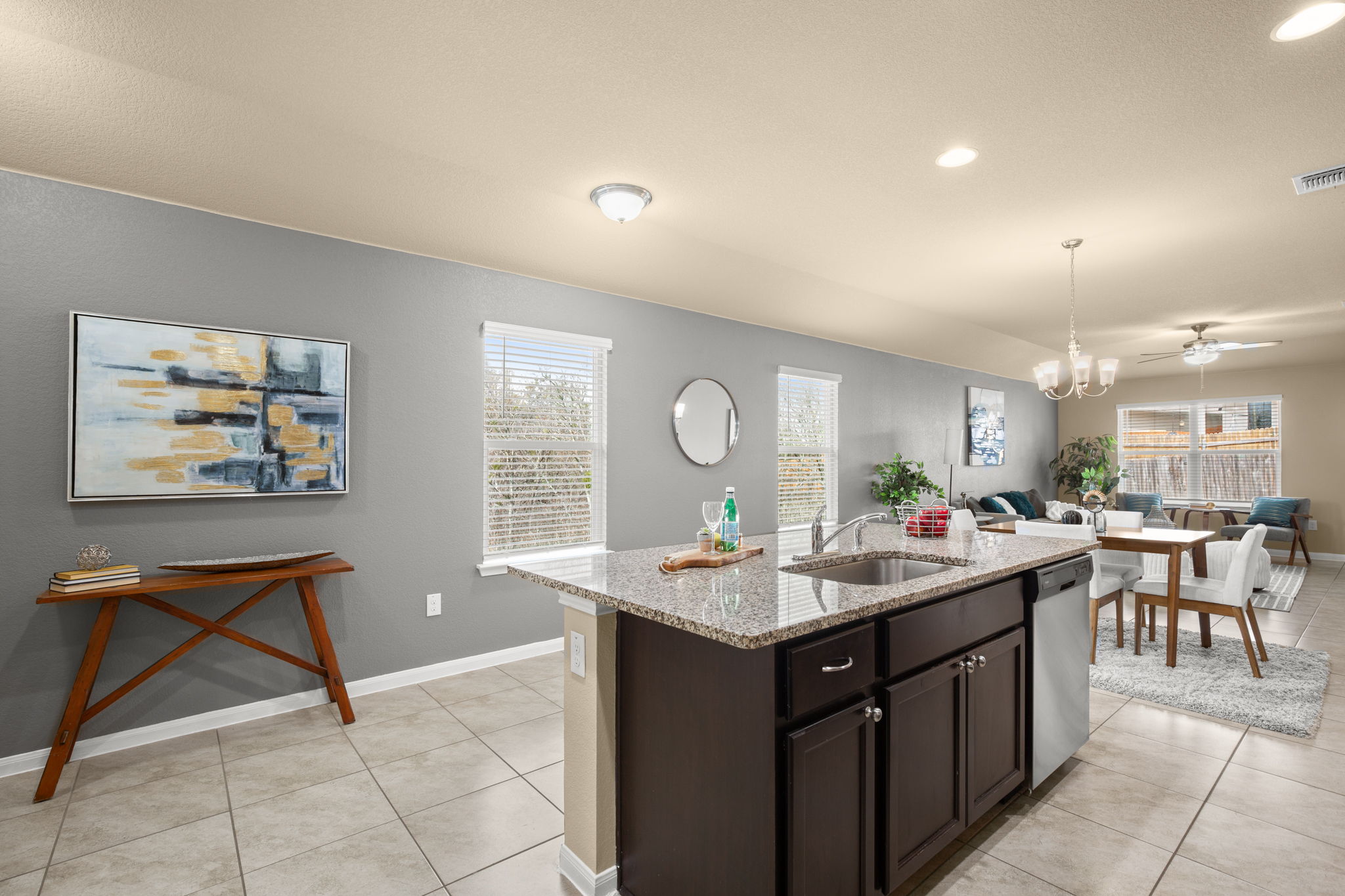 3100 Crystal Bend Drive Pflugerville, TX 78660 - Photo 31 of 32 Kitchen with dark brown cabinets, light stone countertops, light tile patterned flooring, an island with sink, and open floor plan