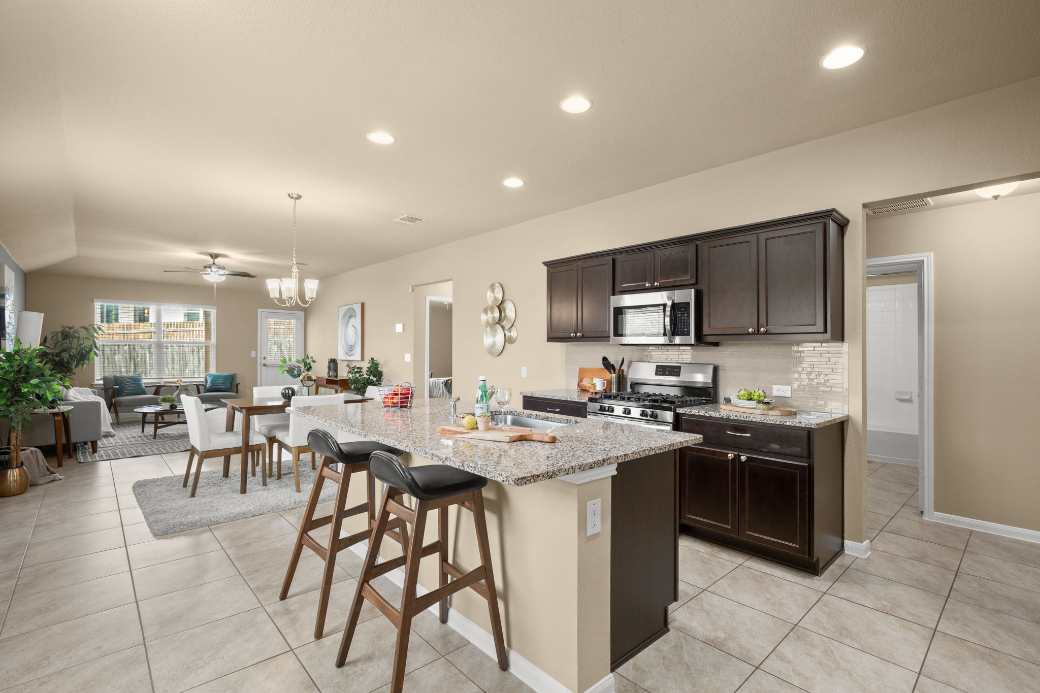 3100 Crystal Bend Drive Pflugerville, TX 78660 - Photo 2 of 32 Kitchen with dark brown cabinetry, light stone countertops, a kitchen island with sink, stainless steel appliances, and a kitchen breakfast bar