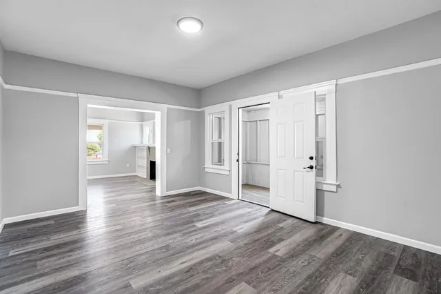 a view of an empty room with wooden floor and closet