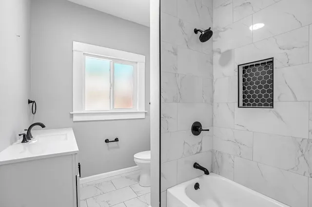 a bathroom with a bathtub shower sink vanity and toilet