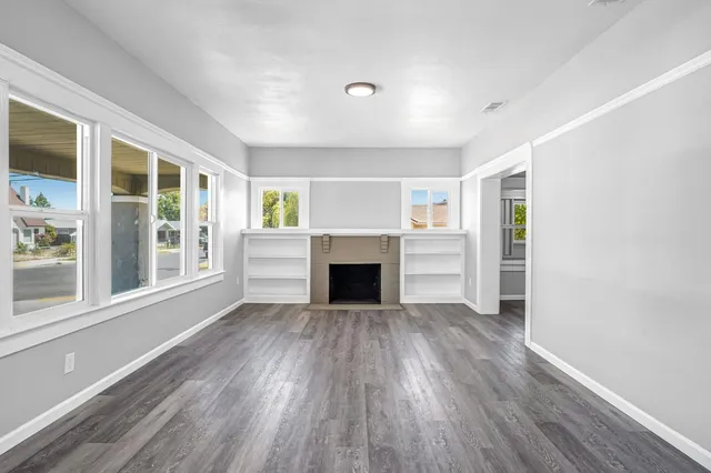wooden floor fireplace and windows in an empty room