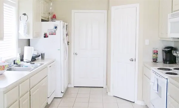 a kitchen with white cabinets and white appliances