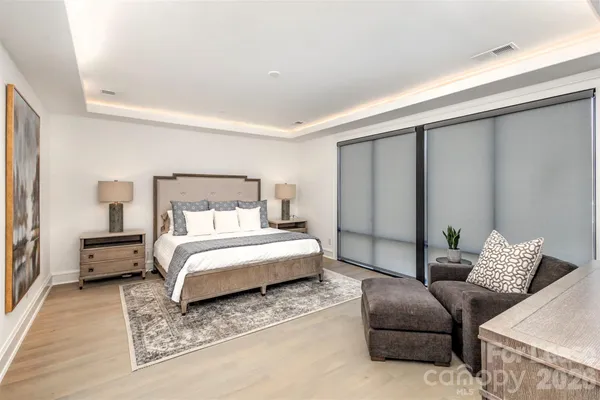 a spacious bedroom with a bed a dresser and a large mirror