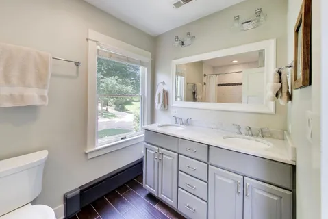 a en suite bathroom with a granite countertop sink toilet a large mirror and a window