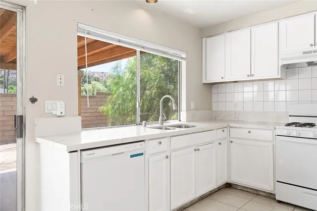a kitchen with white cabinets and a large window