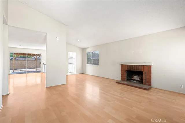 a view of an empty room with a window and fireplace