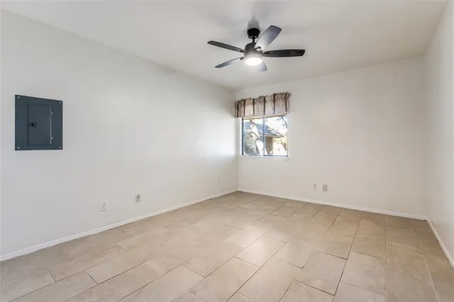 an empty room with windows and chandelier fan