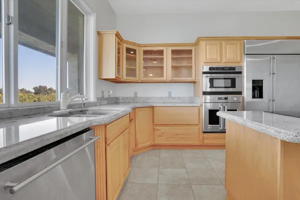 a view of an empty room with a window and kitchen view