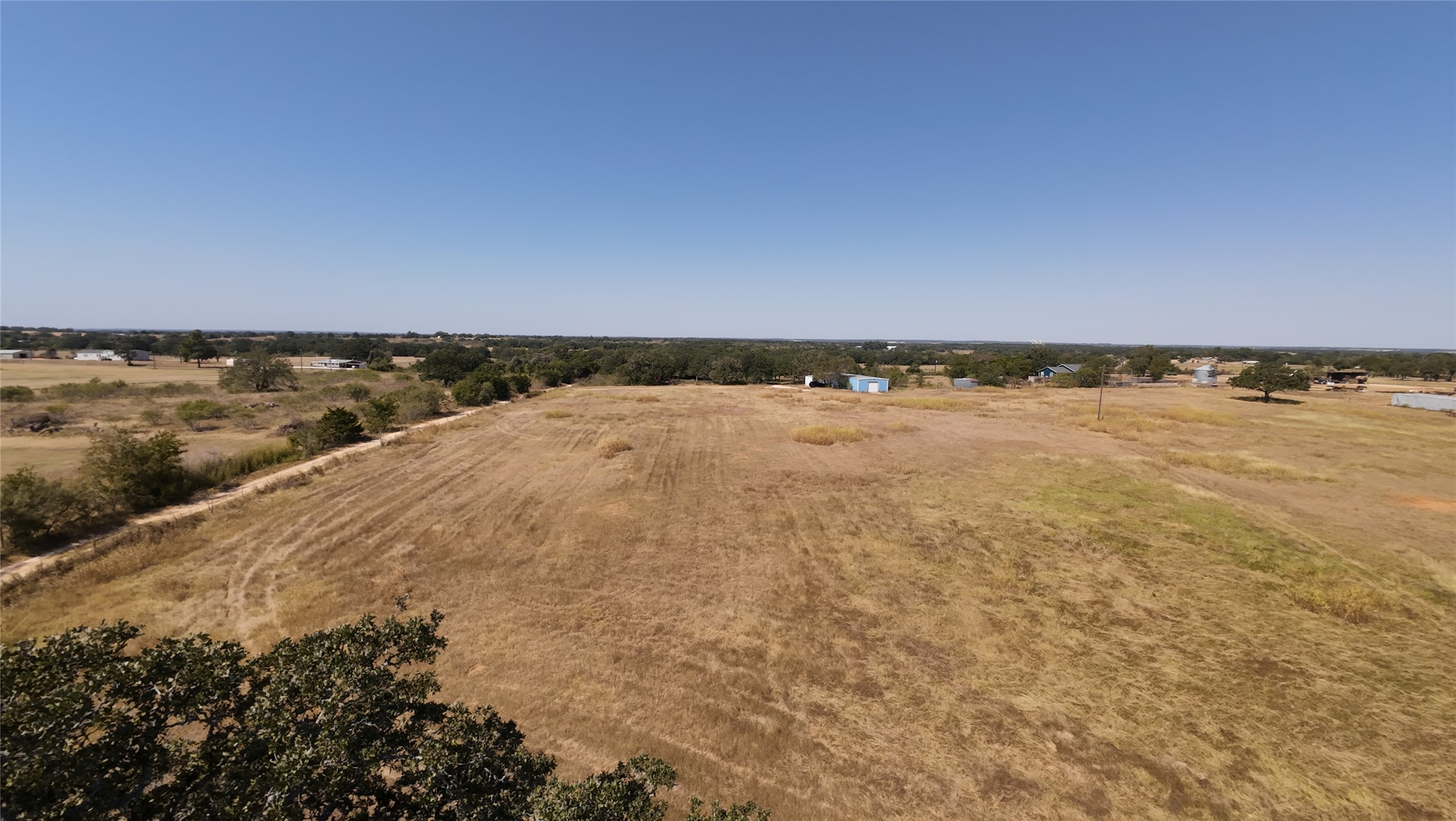 741 Knobbs Road McDade, TX 78650 - Photo 38 of 38 A sprawling vacant lot awaits new construction, offering open skies and distant tree lines.