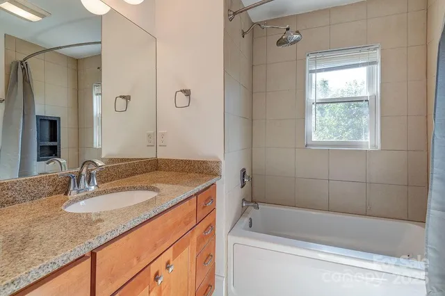 a bathroom with a granite countertop sink mirror bathtub and shower