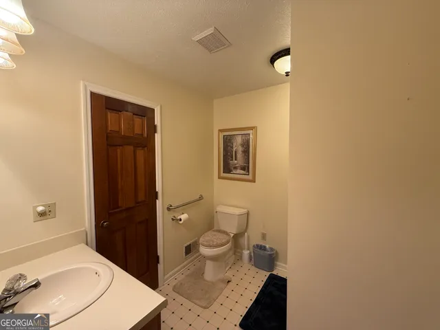 a bathroom with a granite countertop toilet and a sink