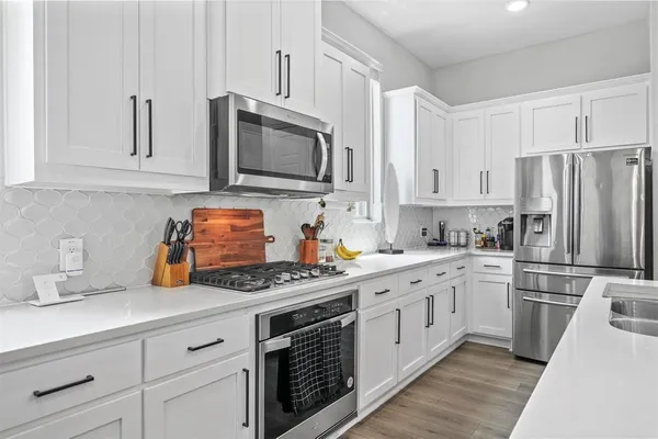 a kitchen with stainless steel appliances white cabinets and wooden floors