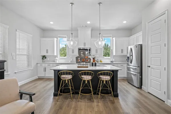 a kitchen with stainless steel appliances granite countertop a table chairs stove a sink dishwasher a refrigerator and microwave with wooden floor