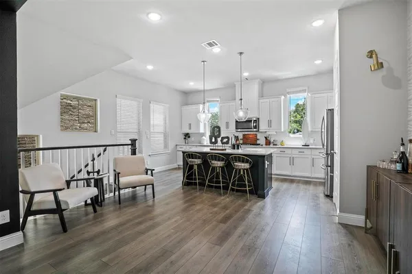 a open kitchen with stainless steel appliances granite countertop a stove a refrigerator a kitchen island a dining table and chairs with wooden floor